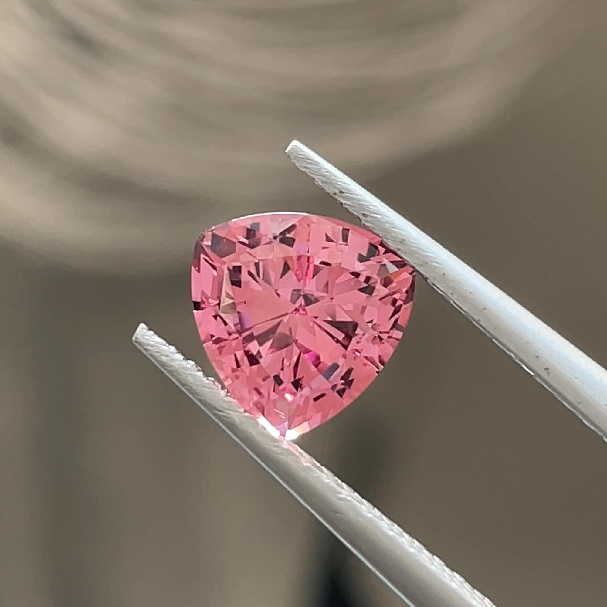 Precision Cut 1.73 ct Pink Mahenge Garnet from Tanzania, Trillion cut, tweezer shot grey background
