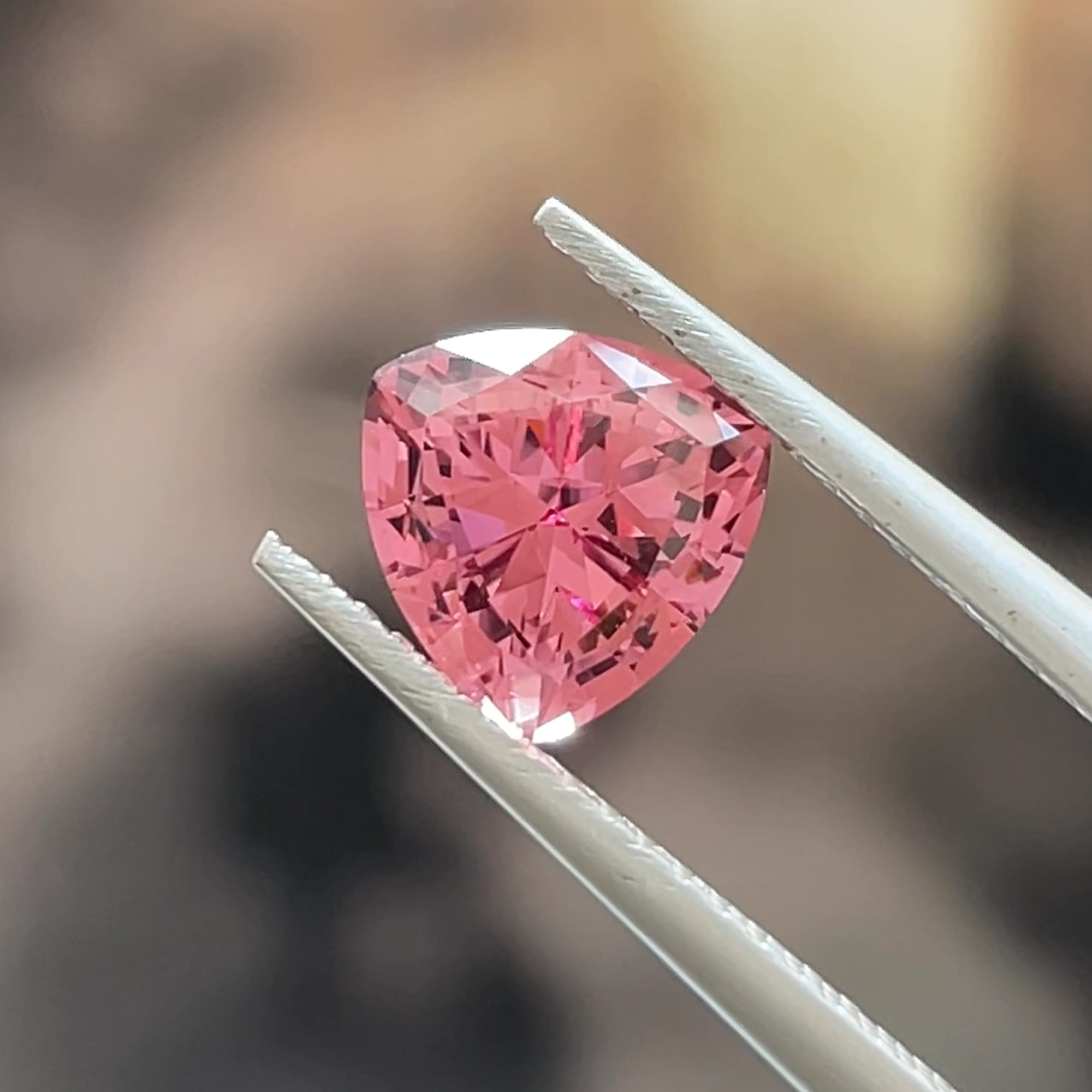 Precision Cut 1.73 ct Pink Mahenge Garnet from Tanzania, Trillion cut, tweezer shot beige background