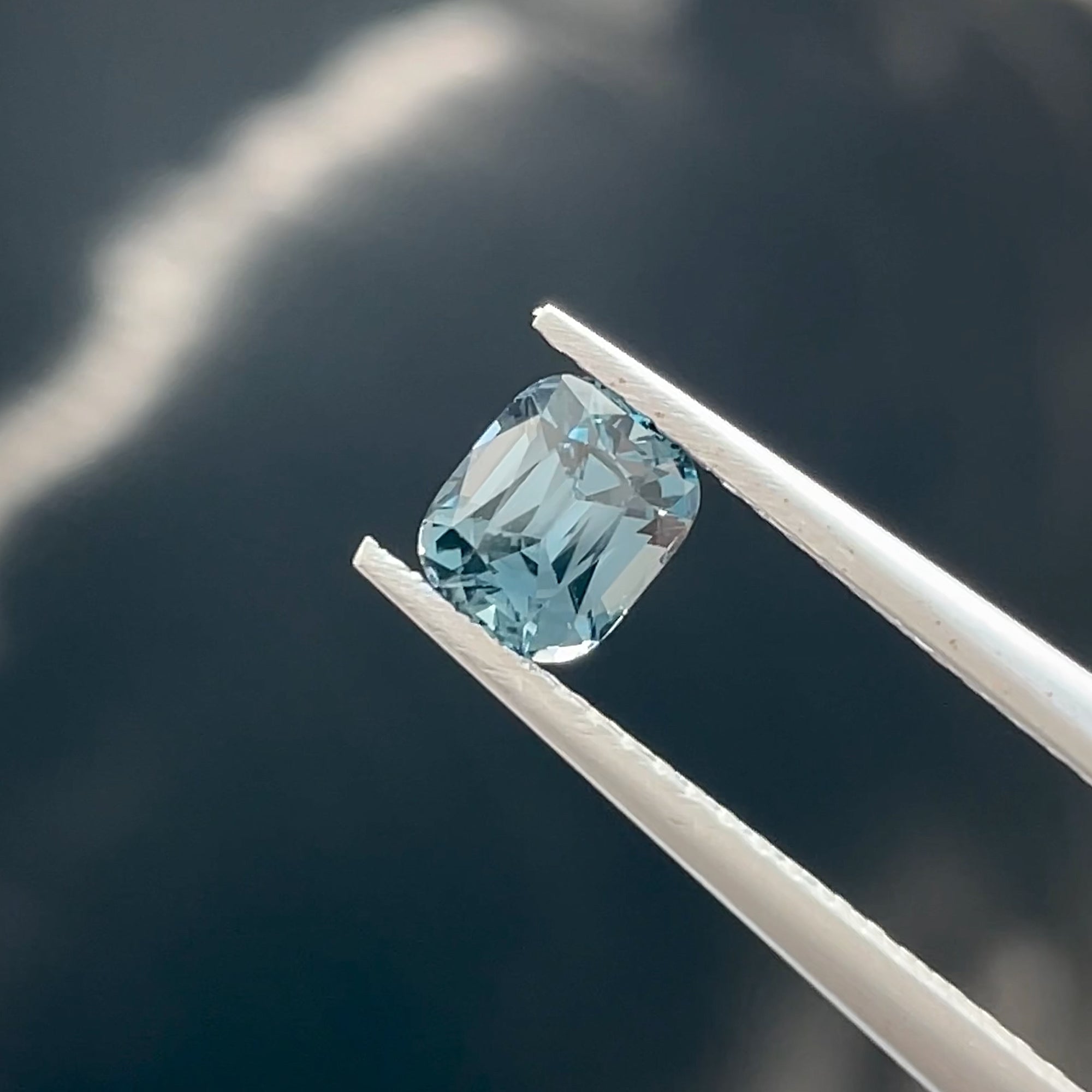 Precision Cut 0.78 ct Teal Spinel from Mahenge Tanzania, tweezer view, black background