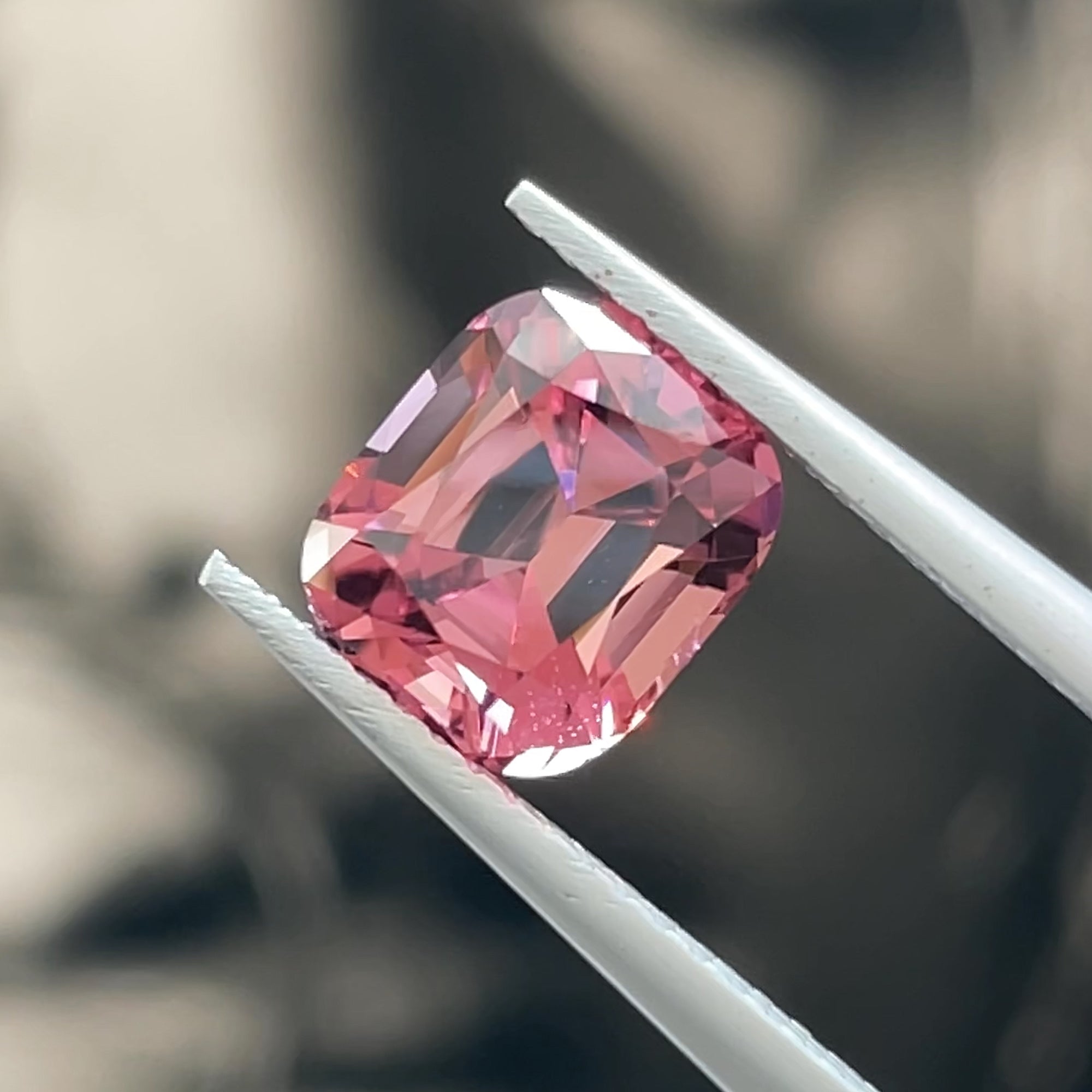 Precision Cut Magenta Pink Tourmaline from Congo, tweezers view, grey background