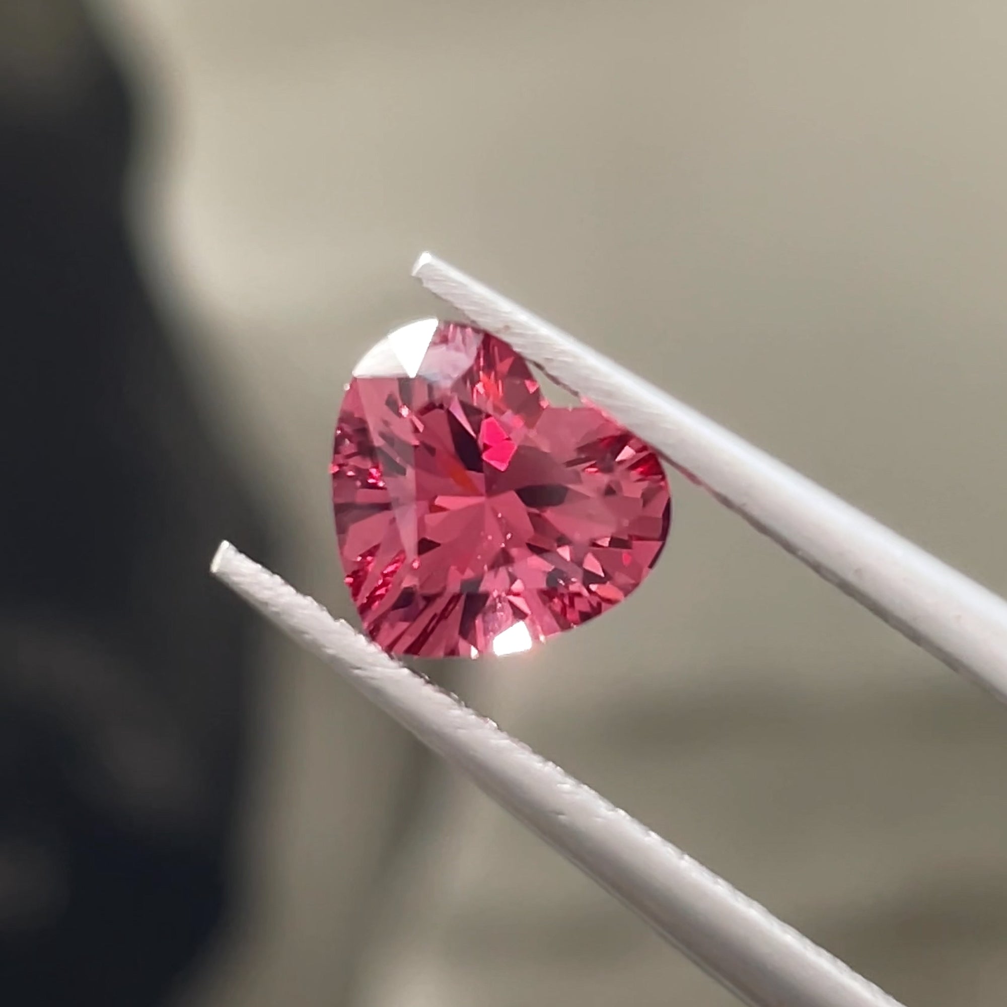 1.32 ct Purplish Pink Malaya Garnet from Tanzania, precision cut, tweezers view, neutral grey background