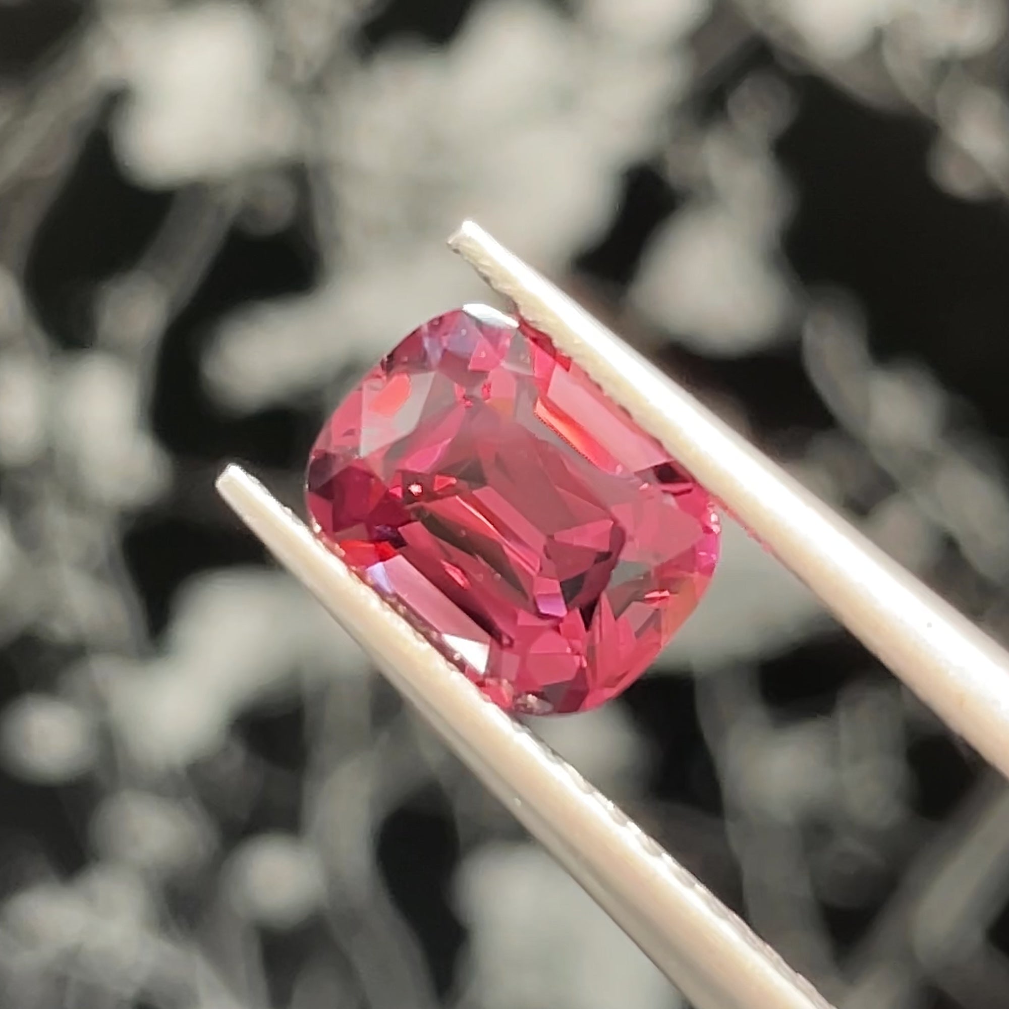1.72 ct Malaya Garnet from Tanzania, precision cut, tweezers view, beige background, black background