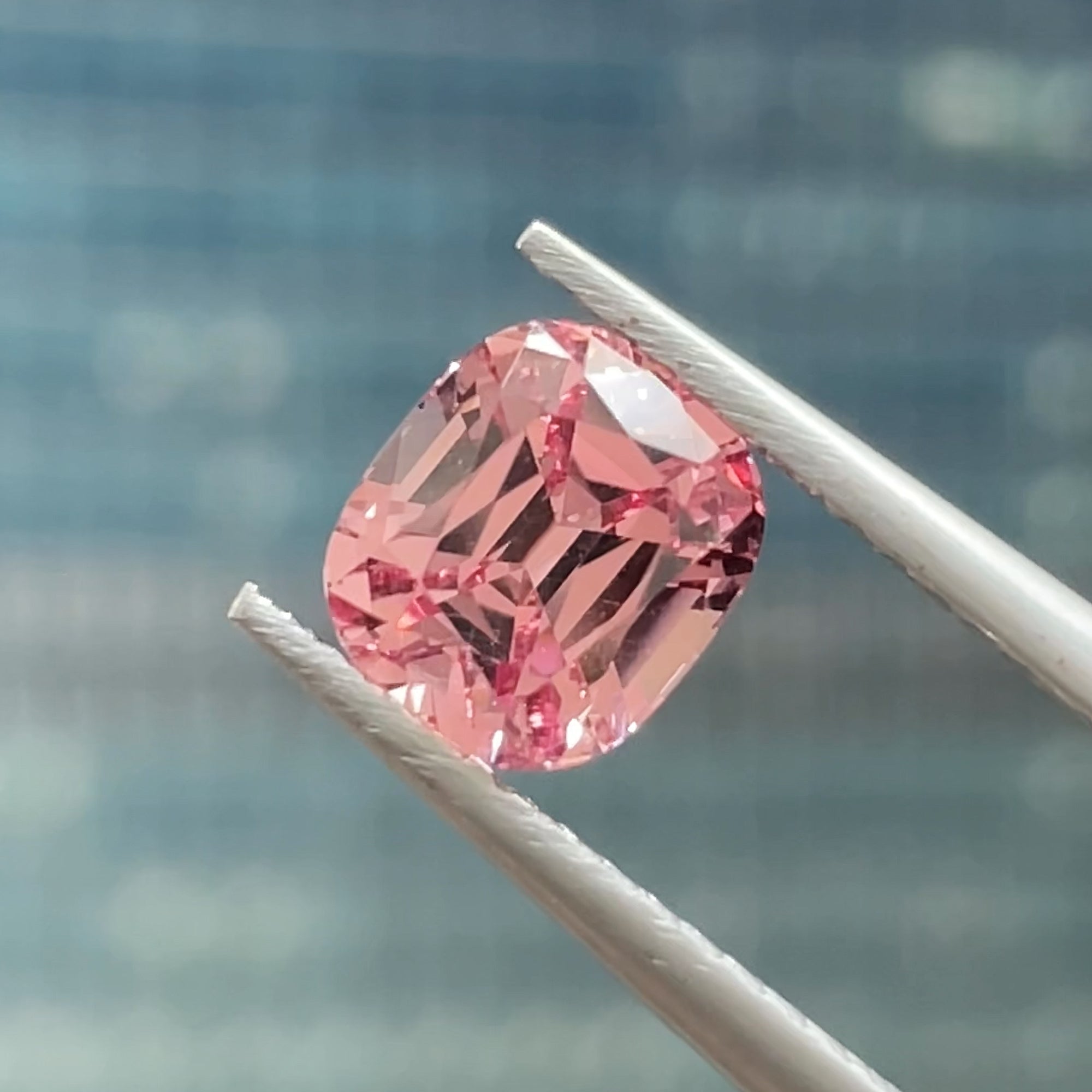 1.77 ct Malaya Mahenge Garnet, Precision Cut, Tweezers view, blue background