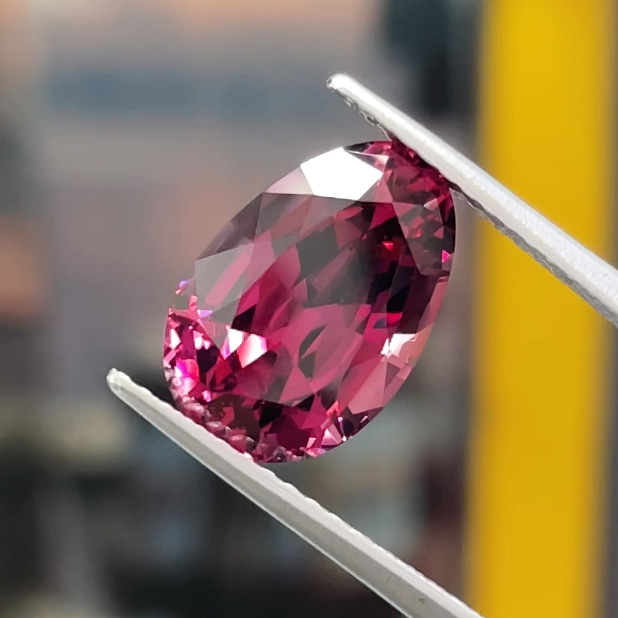 4 carat Precision Cut umbalite Garnet from tanzania, egg shape, tweezers view, neutral bluish background