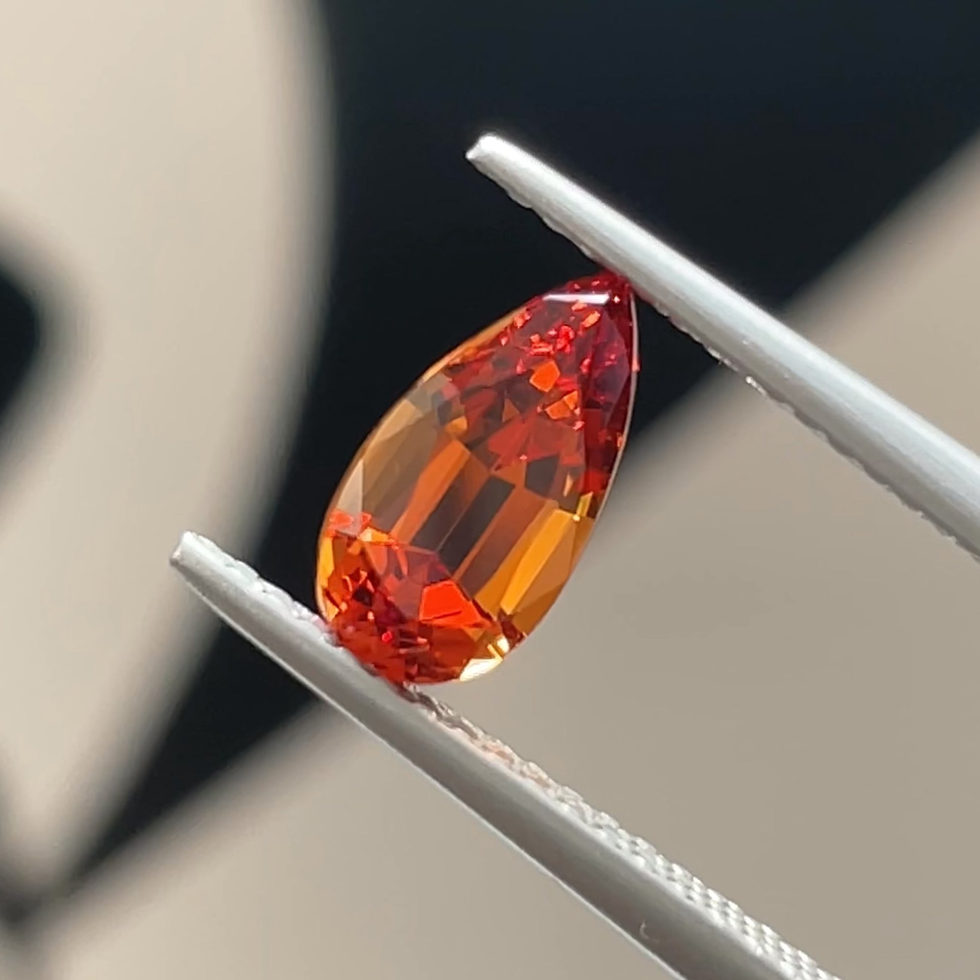 Precision Cut Reddish Orange Malaya garnet from Tanzania, tweezers view, black & white background