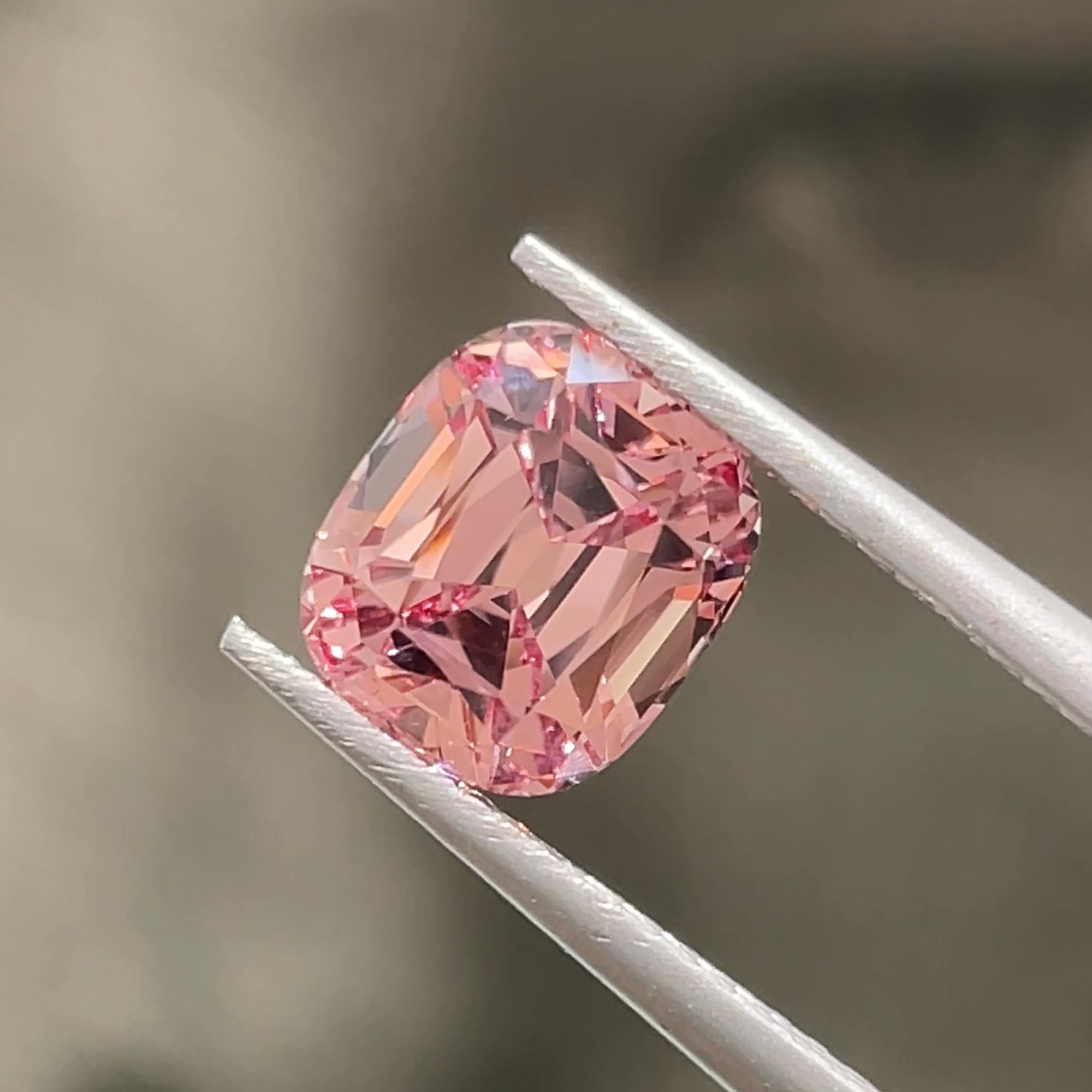 Precision cut 2.72 carat Malaya Mahenge Garnet from Tanzania, Tweezers view, grey background