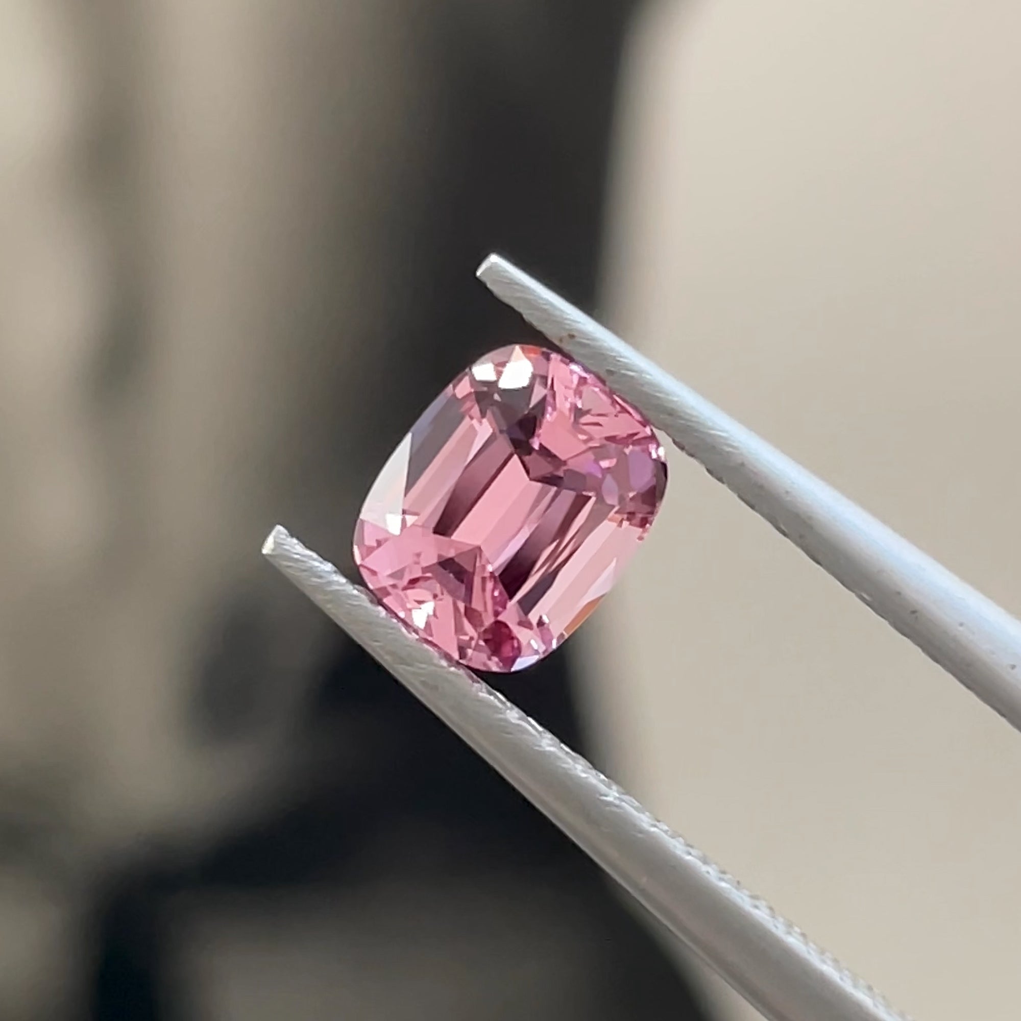 Precision Cut Rose Pink Spinel from Vietnam under direct light, tweezers view, neutral grey background