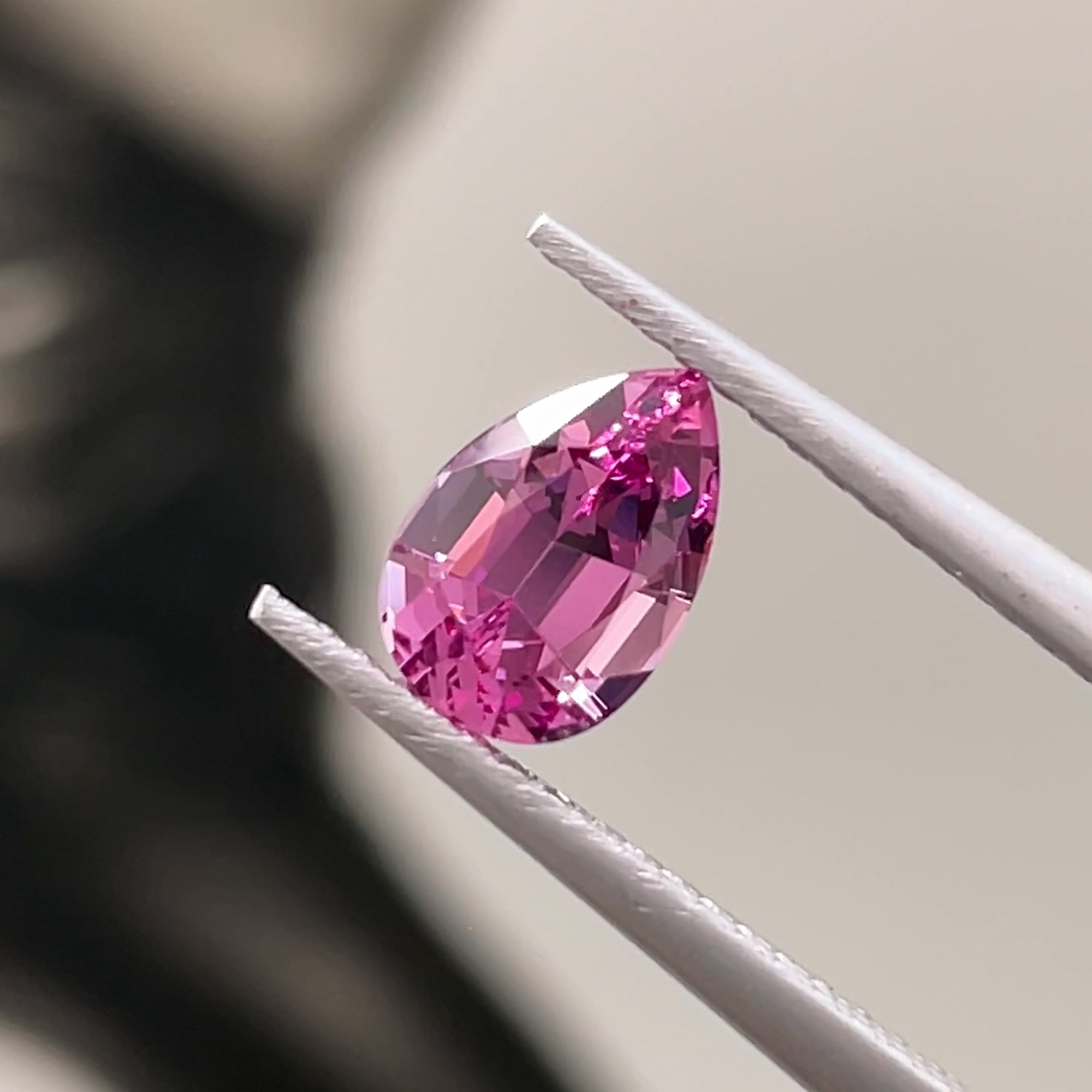 1.27 ct Magenta-Pink Lindi garnet from Tanzania, precision cut, tweezers view, neutral grey background