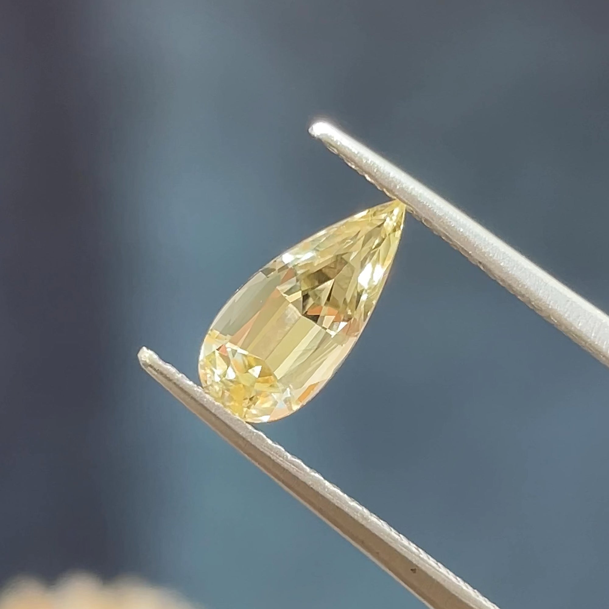 1.28 ct Precision Cut Yellow Chrysoberyl, Pear shape, tweezers view, blue background