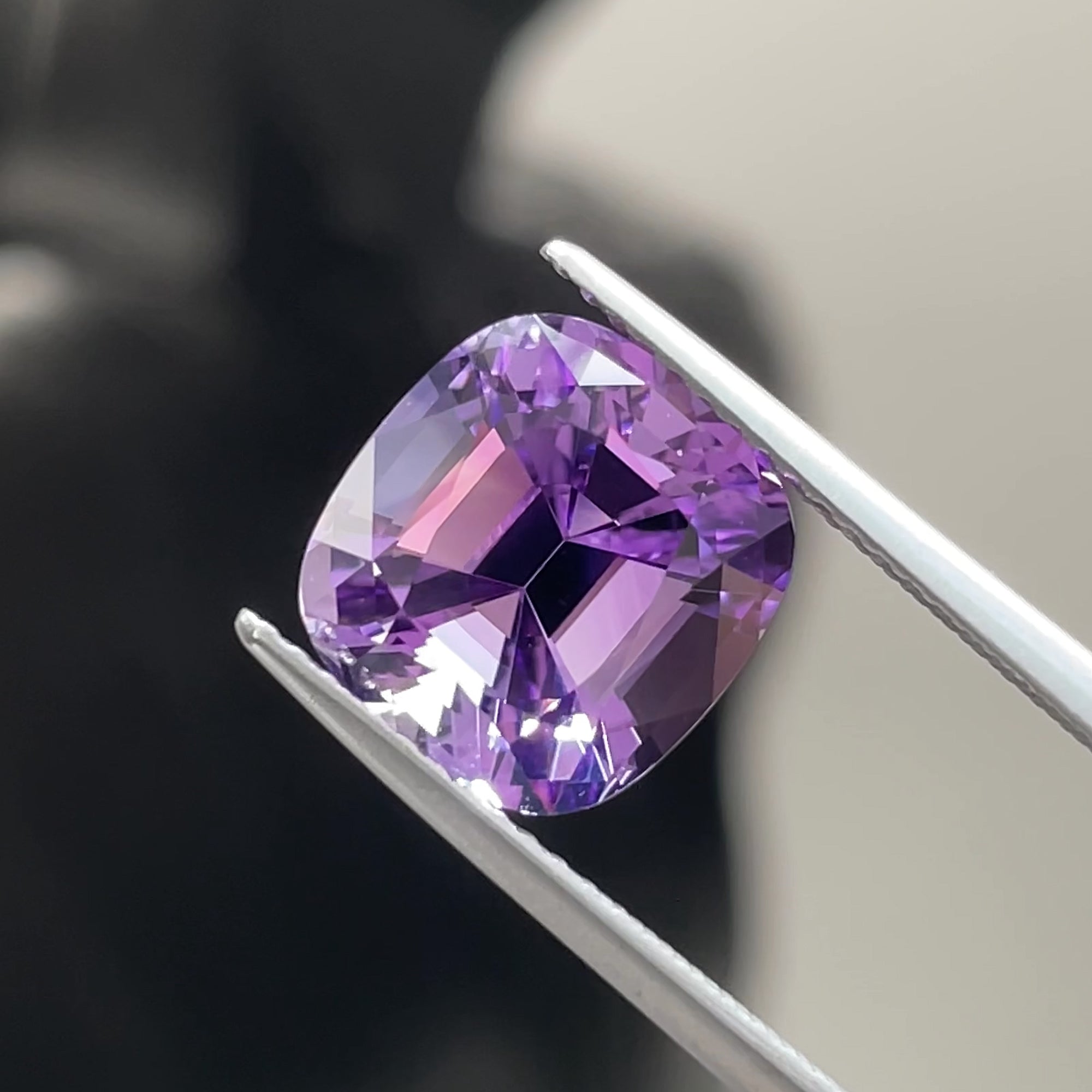 Precision cut 3.92 ct Amethyst cushion from Brazil, tweezers view, black and white background