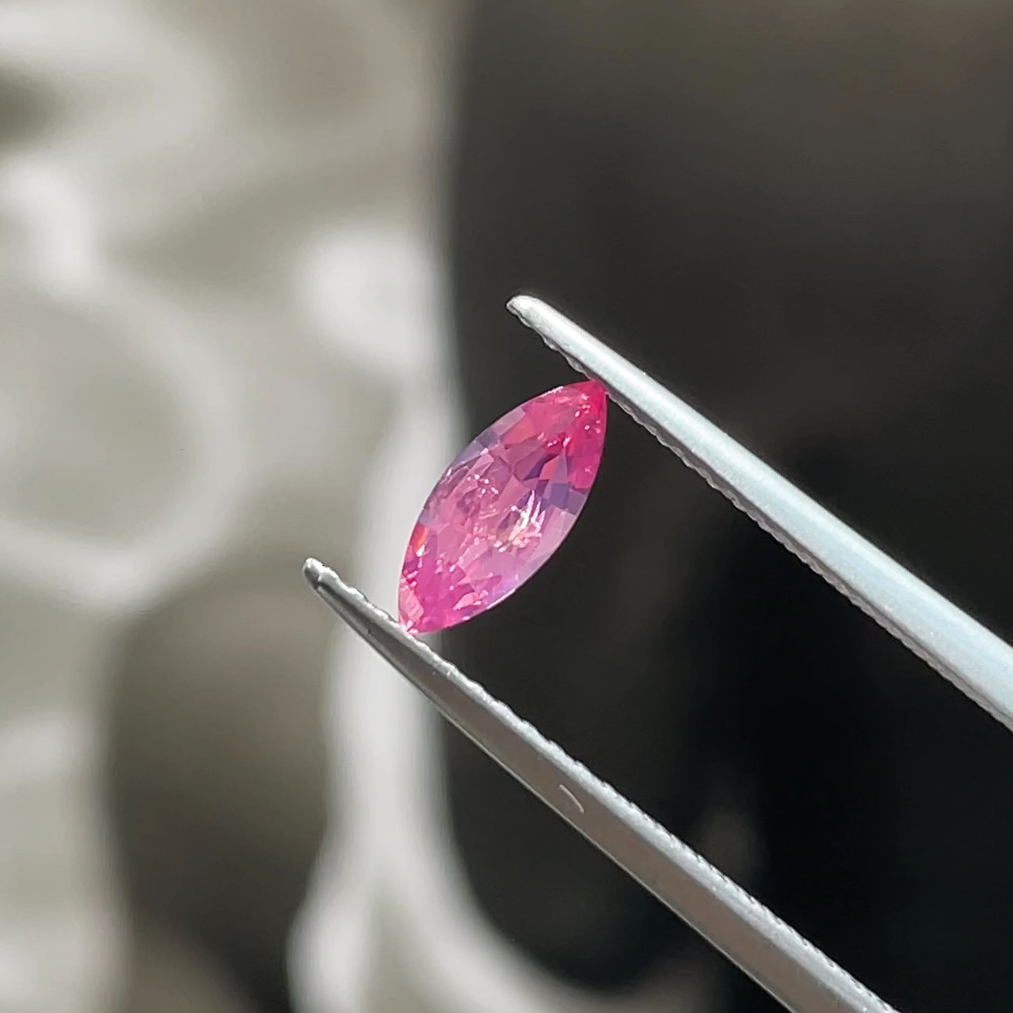 0.41 ct Hot Pink Mahenge Spinel Marquise, precision cut, tweezers view, black and white background